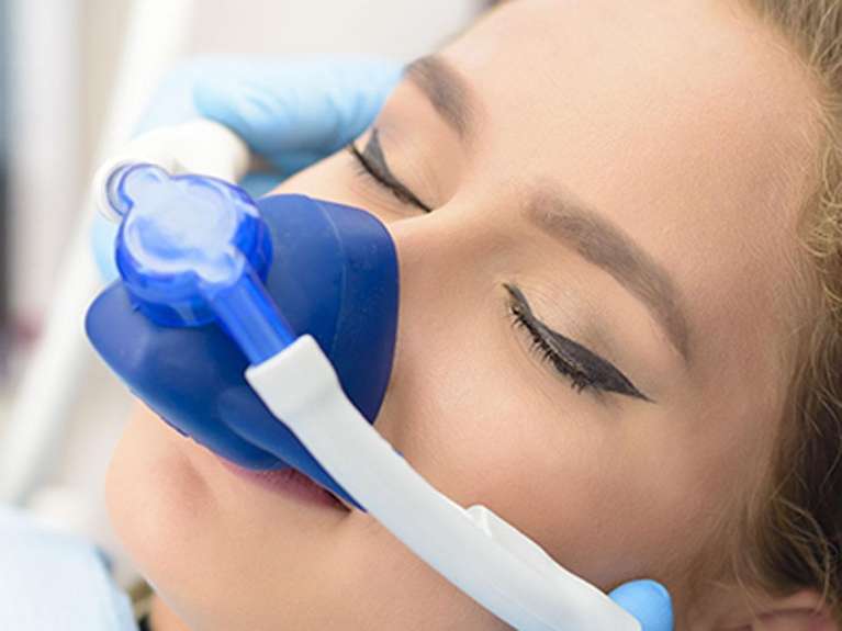 Women inhaling Nitrous Oxide gas with the help of inhaler.